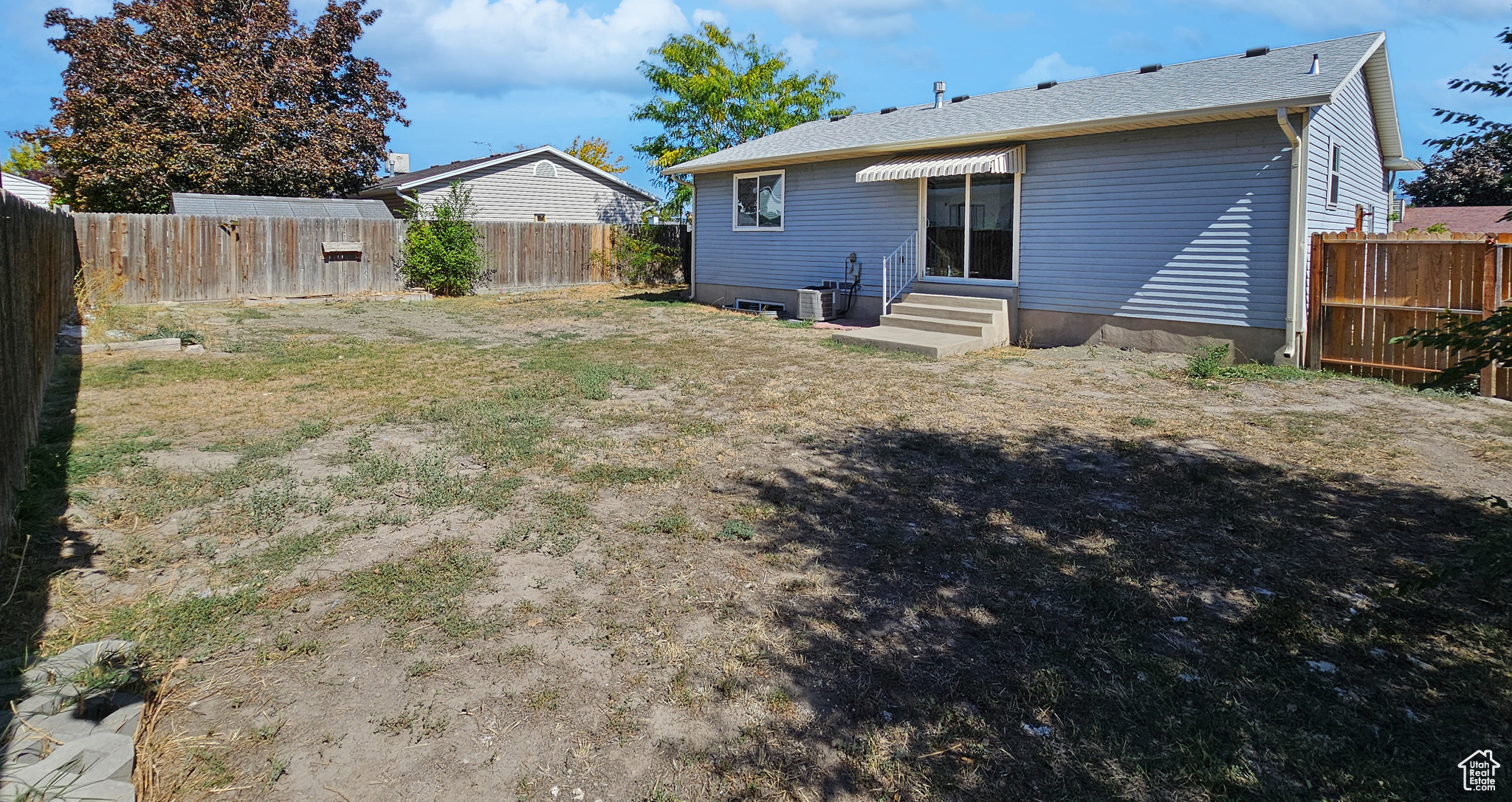 Rear view of house with cooling unit and a yard