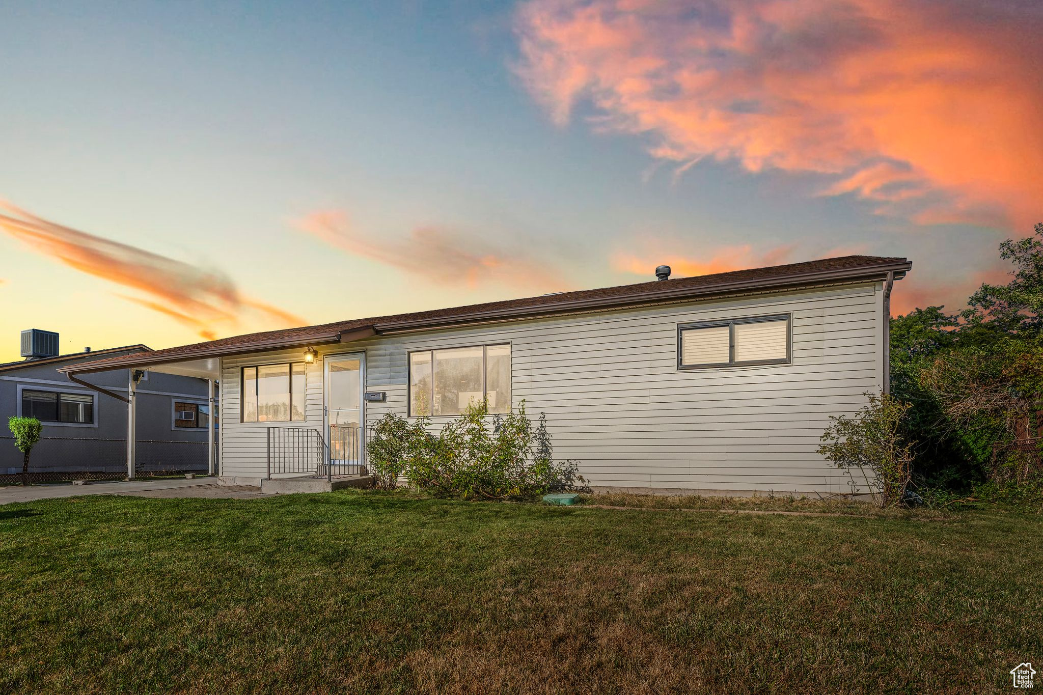 Back house at dusk featuring central AC and a yard