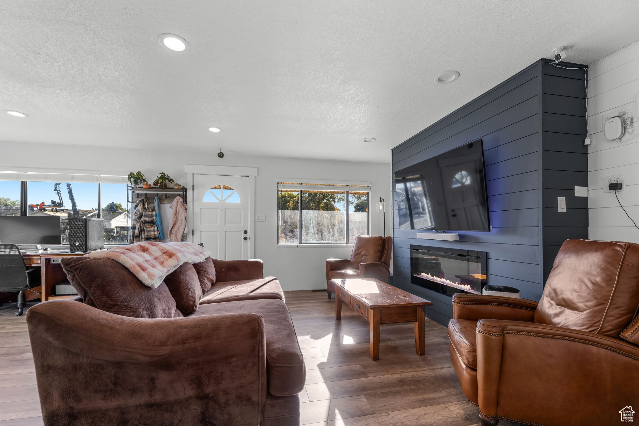 Living room with wood walls, a textured ceiling, and hardwood / wood-style floors