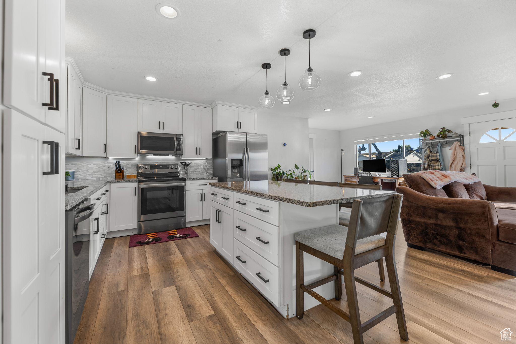 Kitchen featuring light hardwood / wood-style floors, white cabinetry, a breakfast bar, stainless steel appliances, and a center island