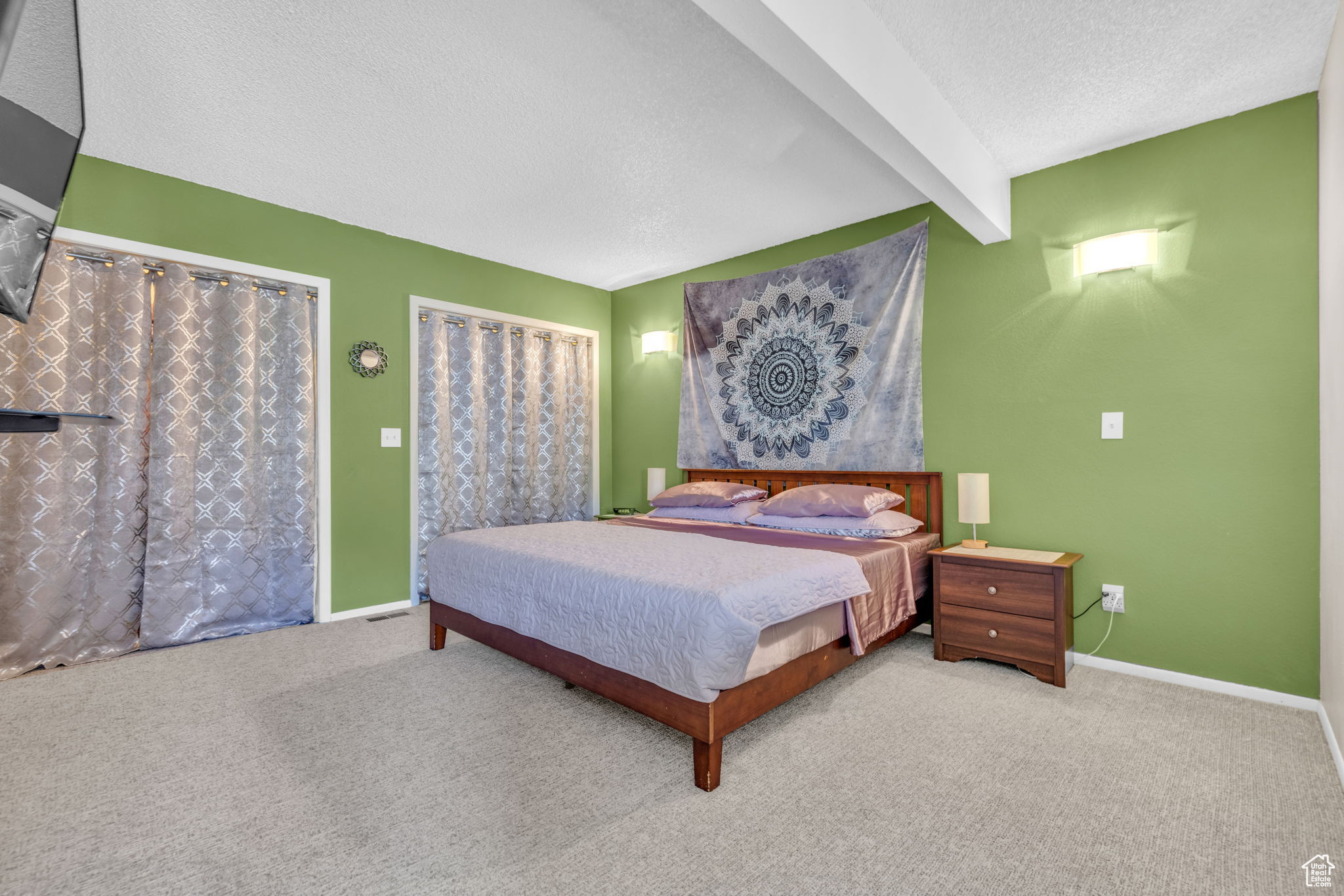 Bedroom featuring light carpet, beam ceiling, and a textured ceiling