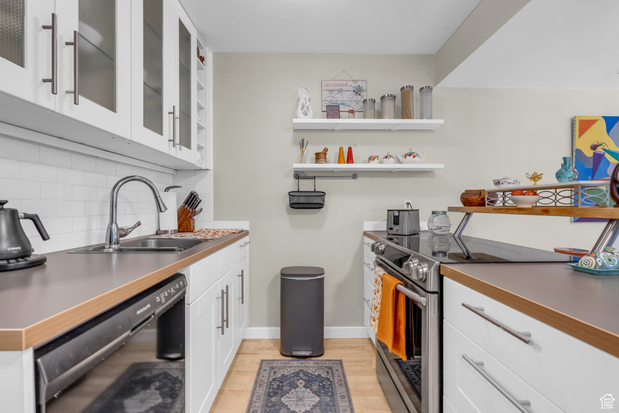 Kitchen featuring white cabinets, light hardwood / wood-style flooring, electric stove, black dishwasher, and decorative backsplash