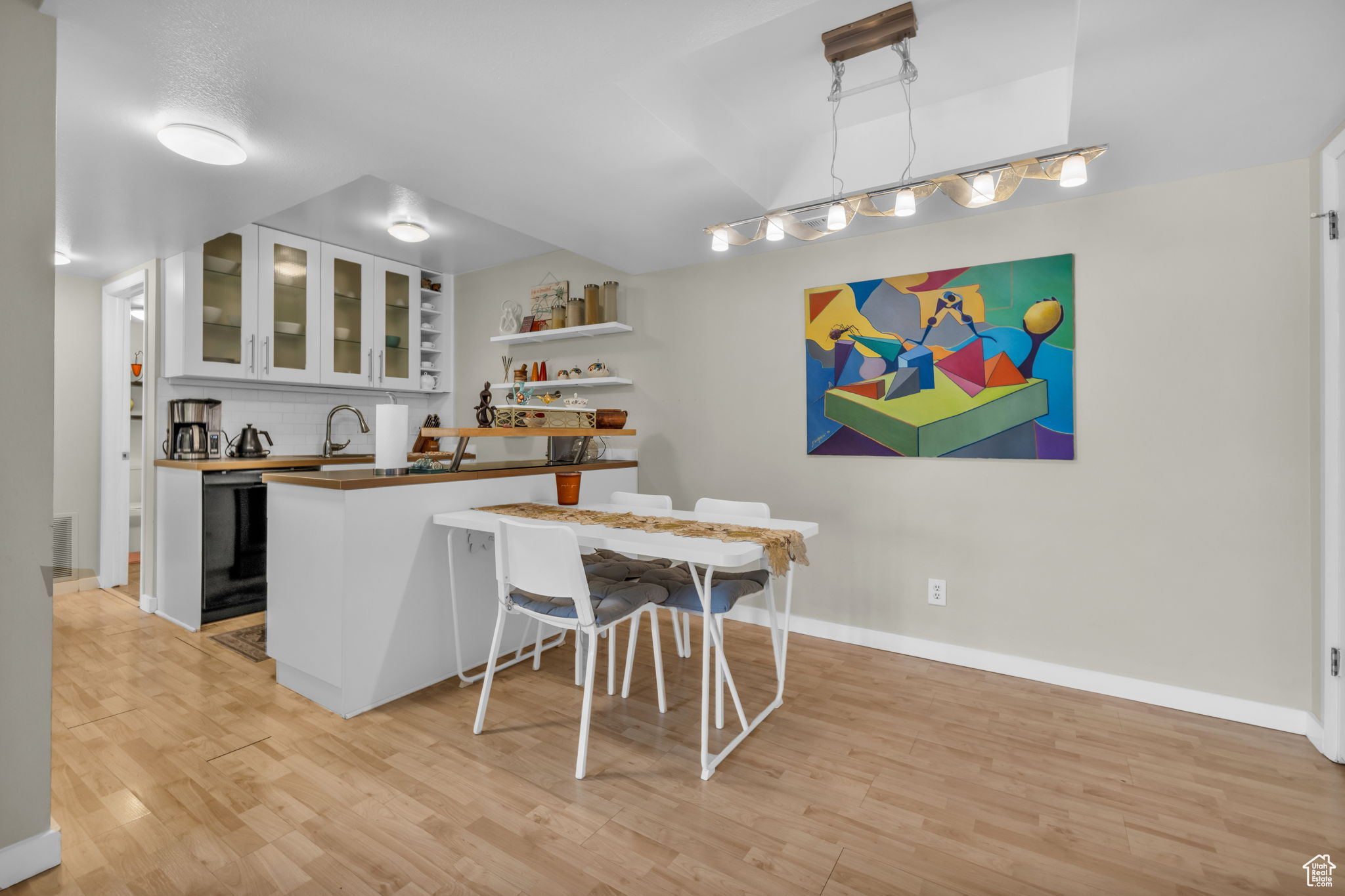 Interior space with light hardwood / wood-style flooring, white cabinets, black dishwasher, and kitchen peninsula