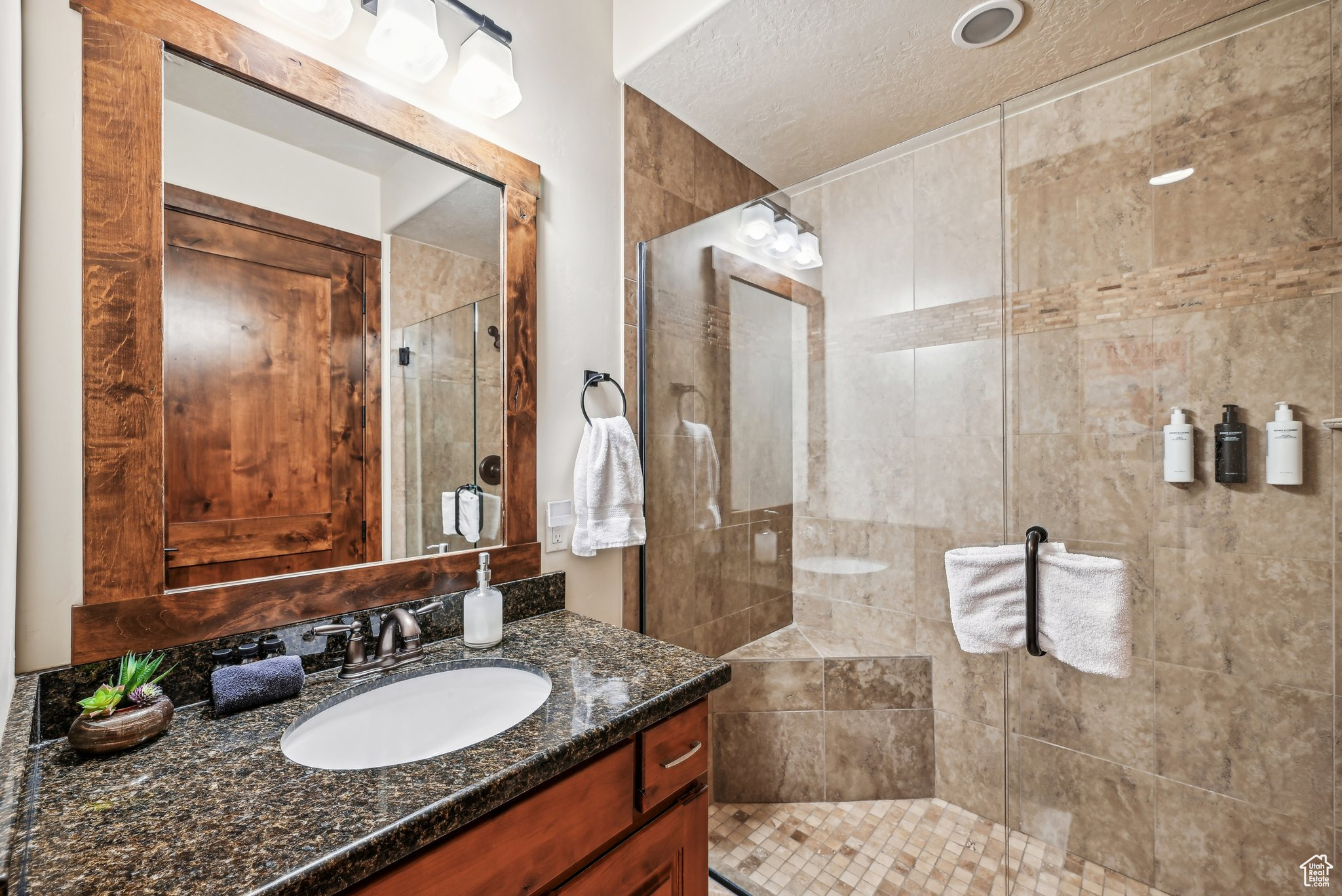 Bathroom with vanity, a textured ceiling, and a shower with door