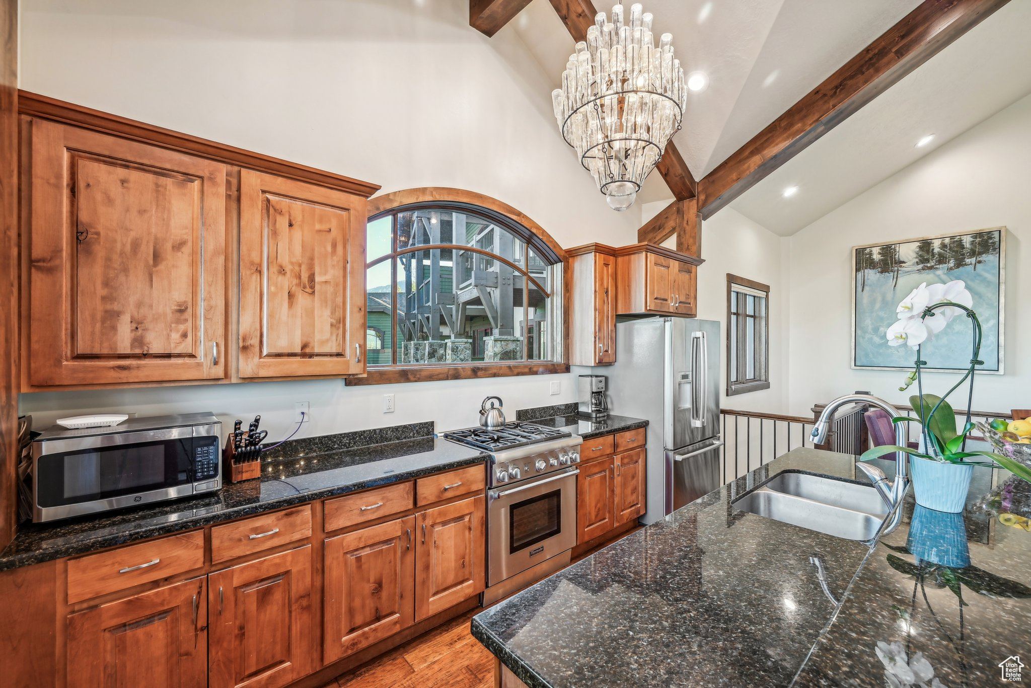 Kitchen featuring pendant lighting, beamed ceiling, sink, a notable chandelier, and stainless steel appliances