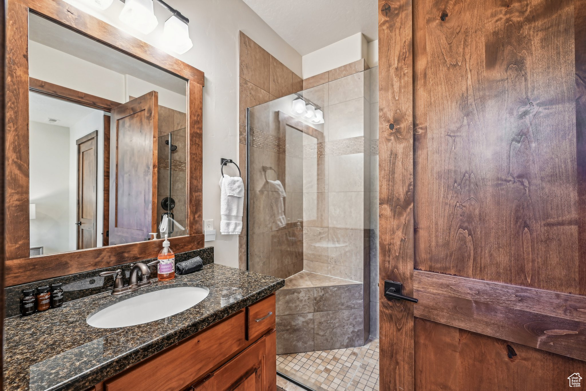 Bathroom with tiled shower, vanity, and tile patterned floors