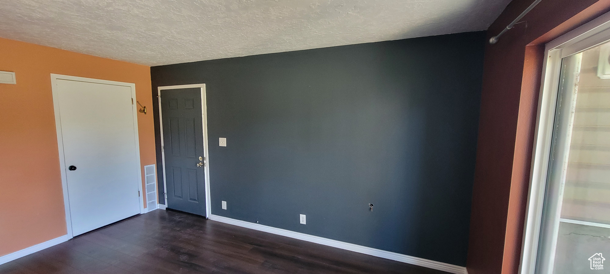 Spare room featuring a textured ceiling and dark wood-type flooring