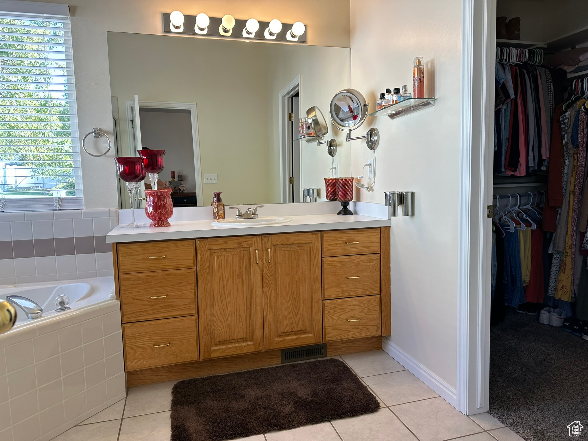 Bathroom featuring tiled tub, vanity, and tile patterned flooring