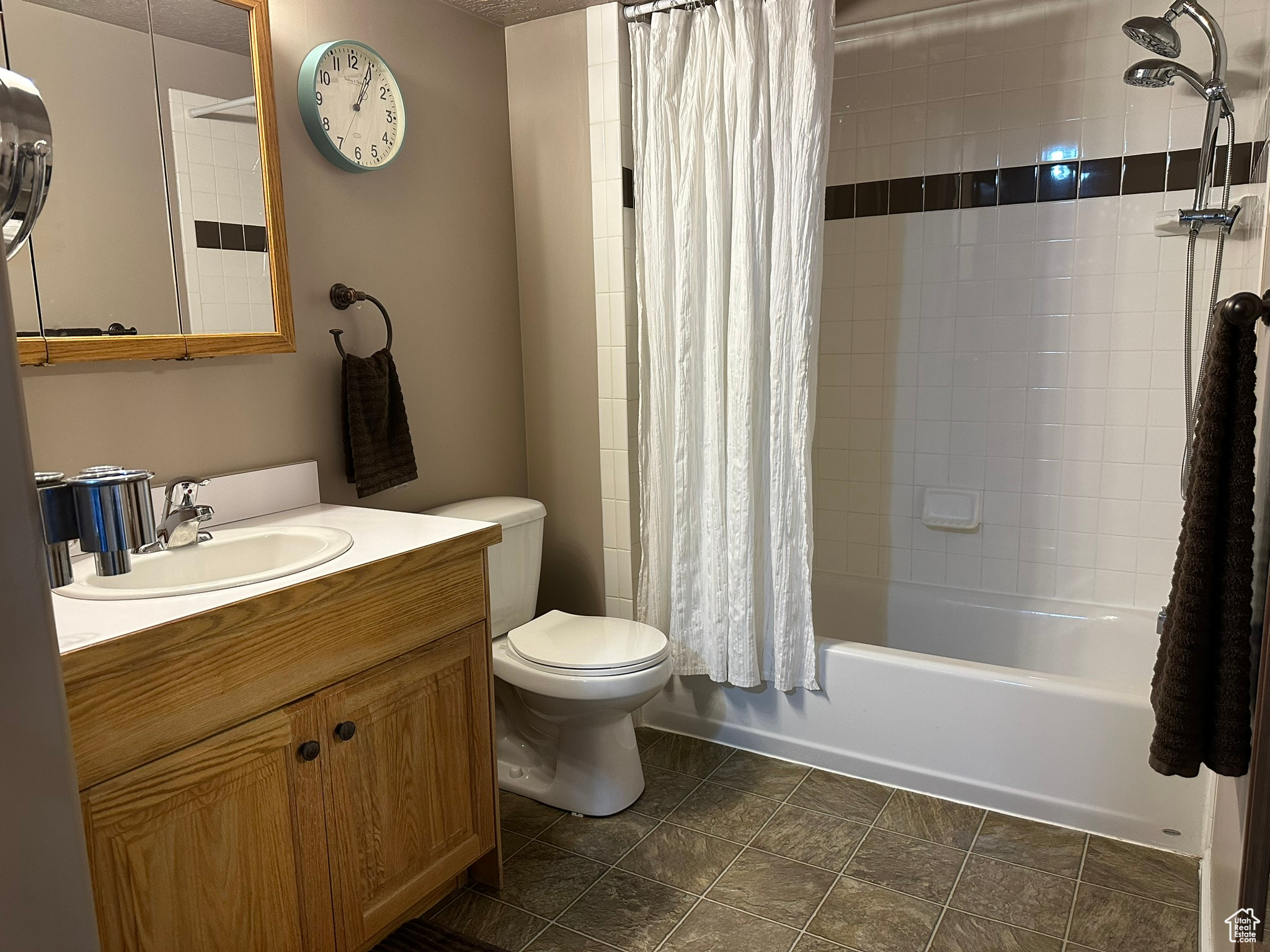 Full bathroom featuring shower / bath combination with curtain, tile patterned flooring, vanity, and toilet