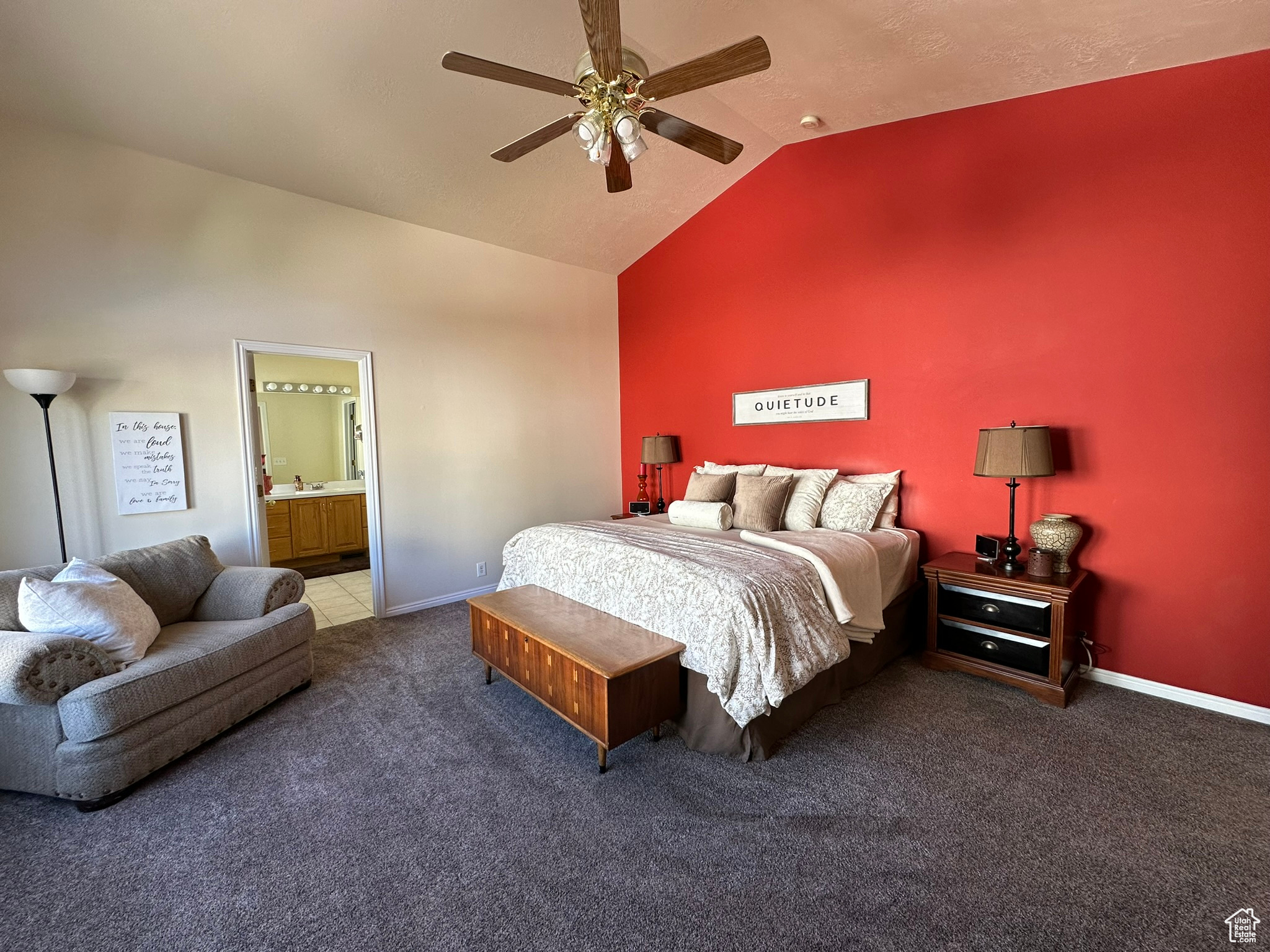 Carpeted bedroom with connected bathroom, vaulted ceiling, ceiling fan, and sink