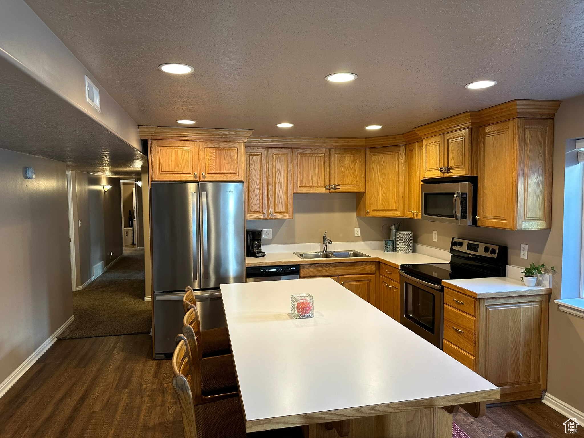 Kitchen featuring a textured ceiling, stainless steel appliances, dark hardwood / wood-style floors, and sink