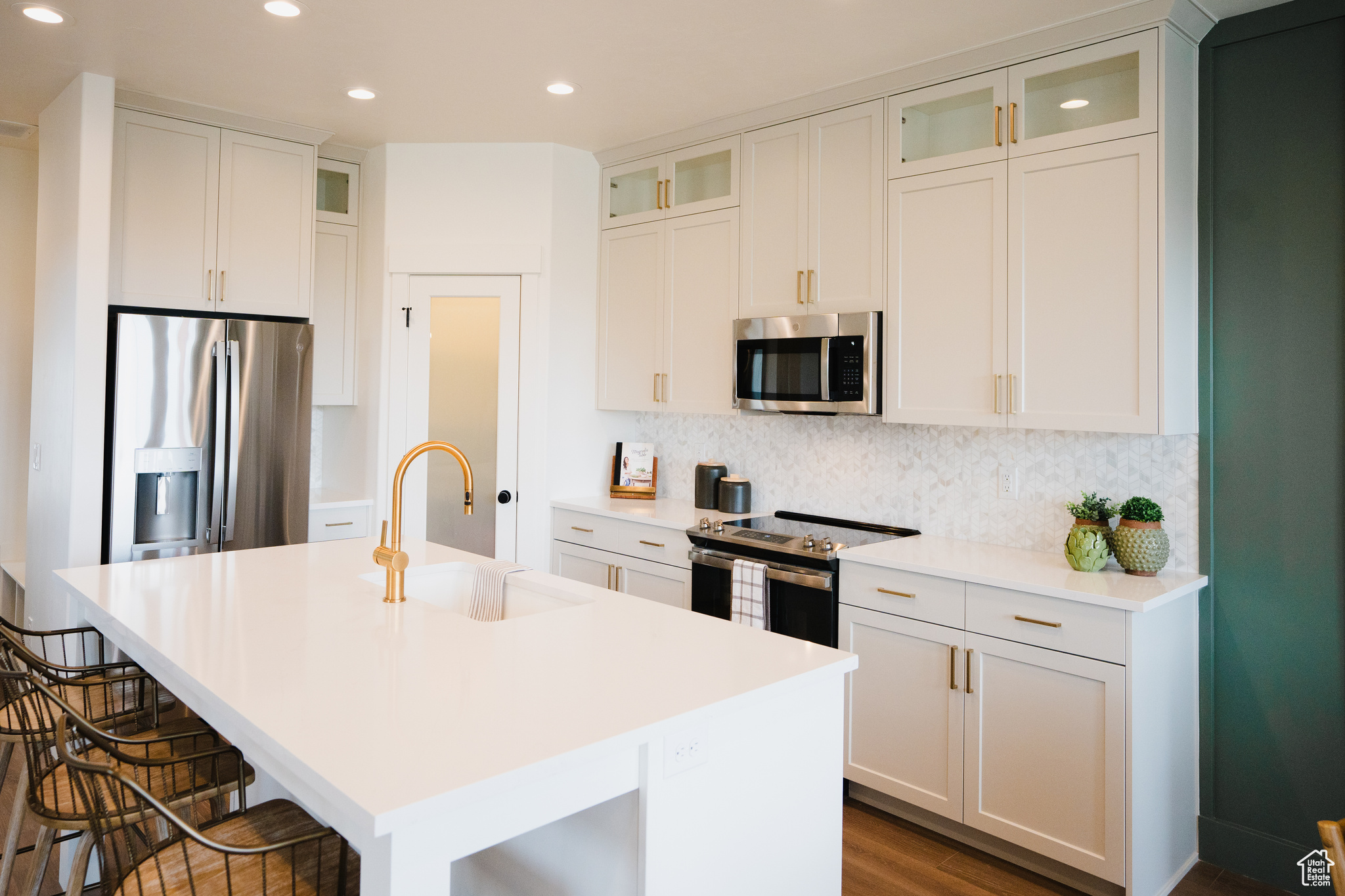 Kitchen featuring white cabinets, sink, a kitchen island with sink, stainless steel appliances, and a breakfast bar