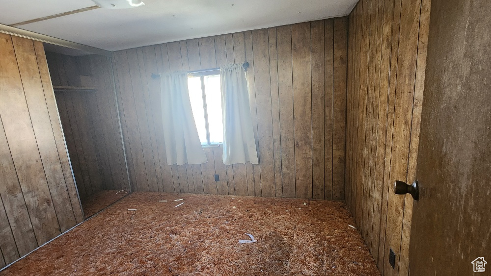 Carpeted empty room featuring wood walls