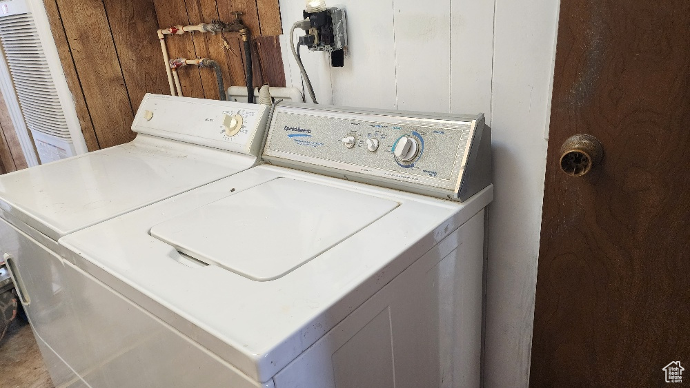 Laundry room with wooden walls and independent washer and dryer