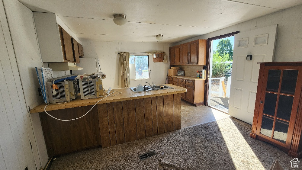 Kitchen featuring kitchen peninsula, wood walls, sink, and plenty of natural light