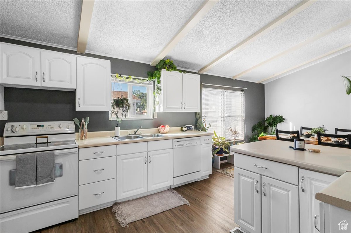 Kitchen featuring white appliances, white cabinets, and a wealth of natural light