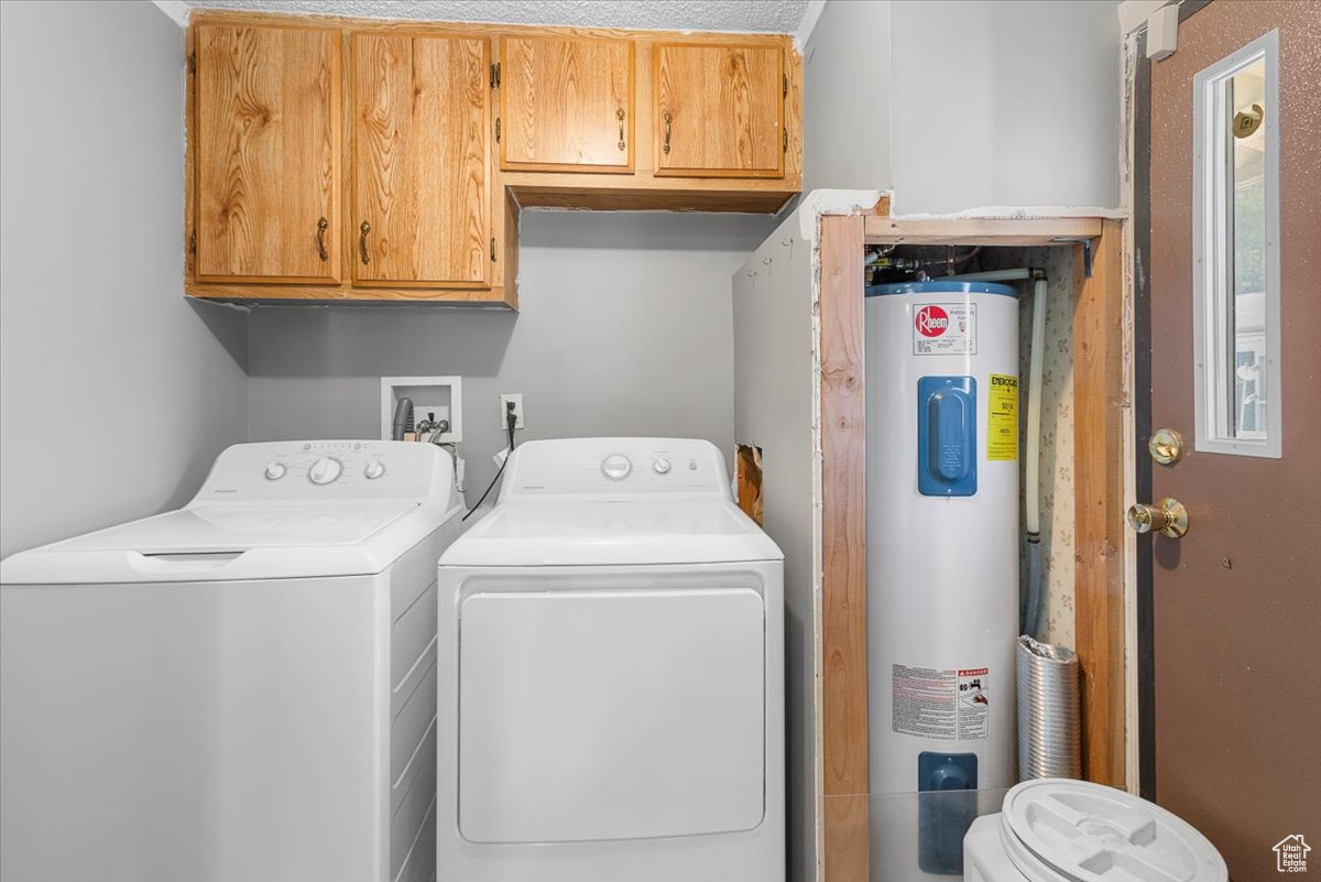 Laundry room with cabinets, electric water heater, and washer and dryer