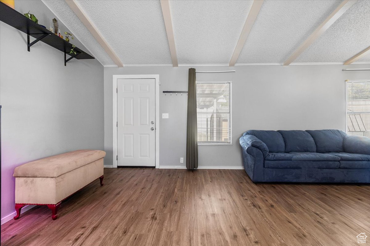 Living room featuring a textured ceiling, wood-type flooring, and beam ceiling