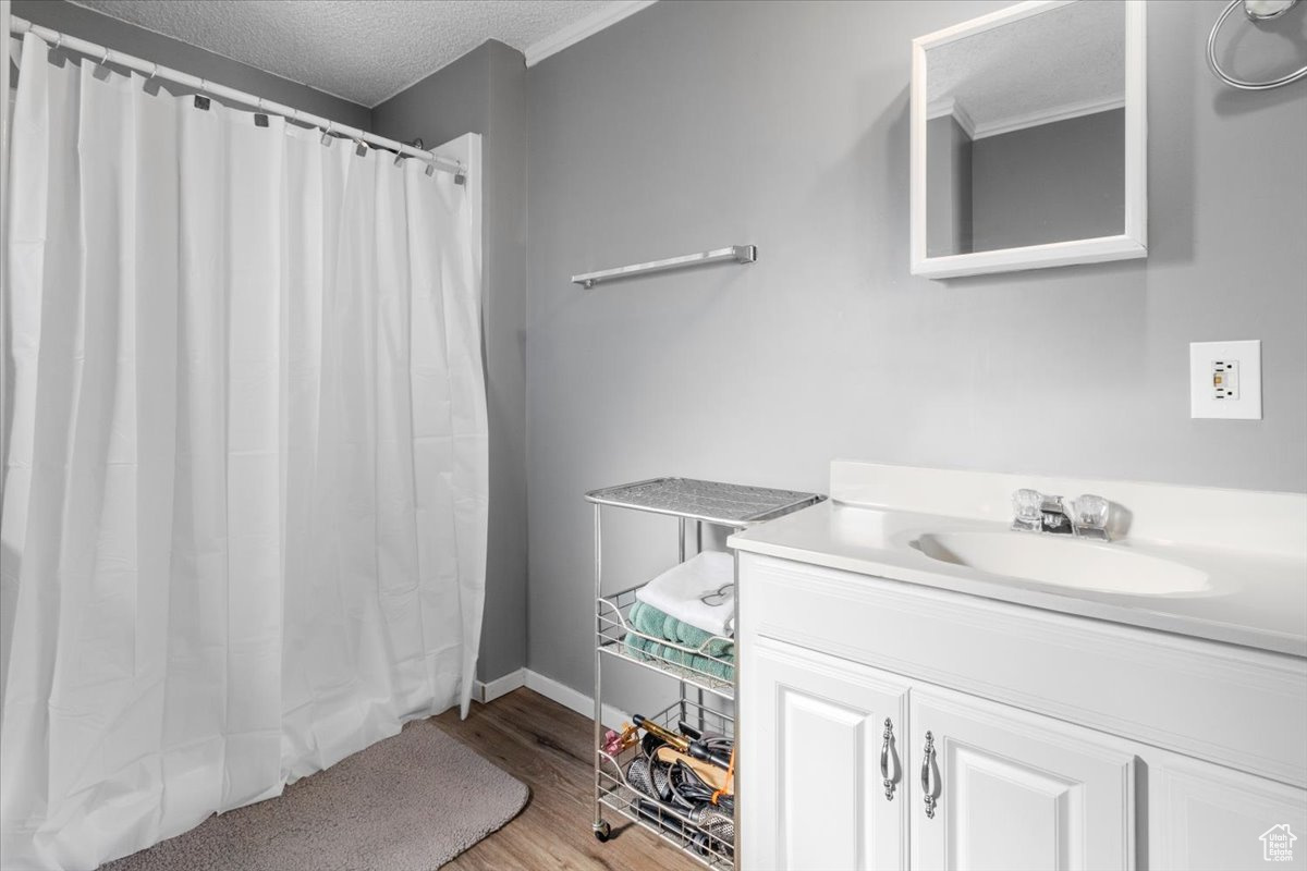 Bathroom with hardwood / wood-style floors, a textured ceiling, walk in shower, and vanity