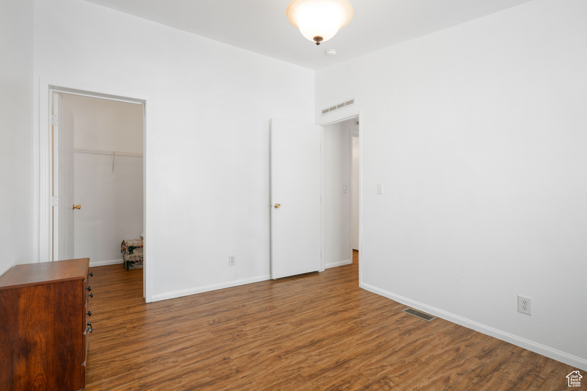 Unfurnished bedroom with a closet, a walk in closet, and hardwood / wood-style floors