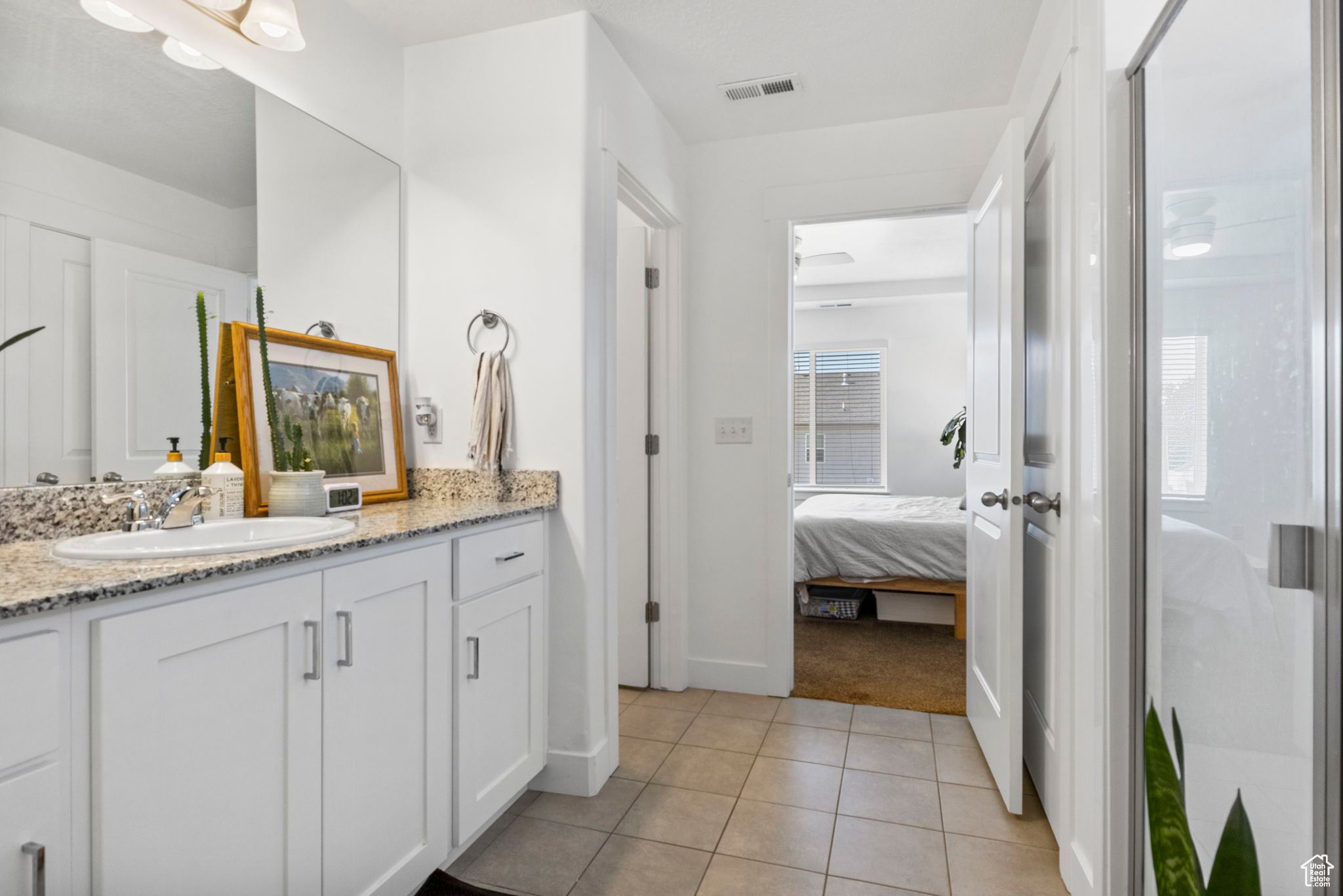 Bathroom featuring tile patterned floors, a shower with door, and vanity