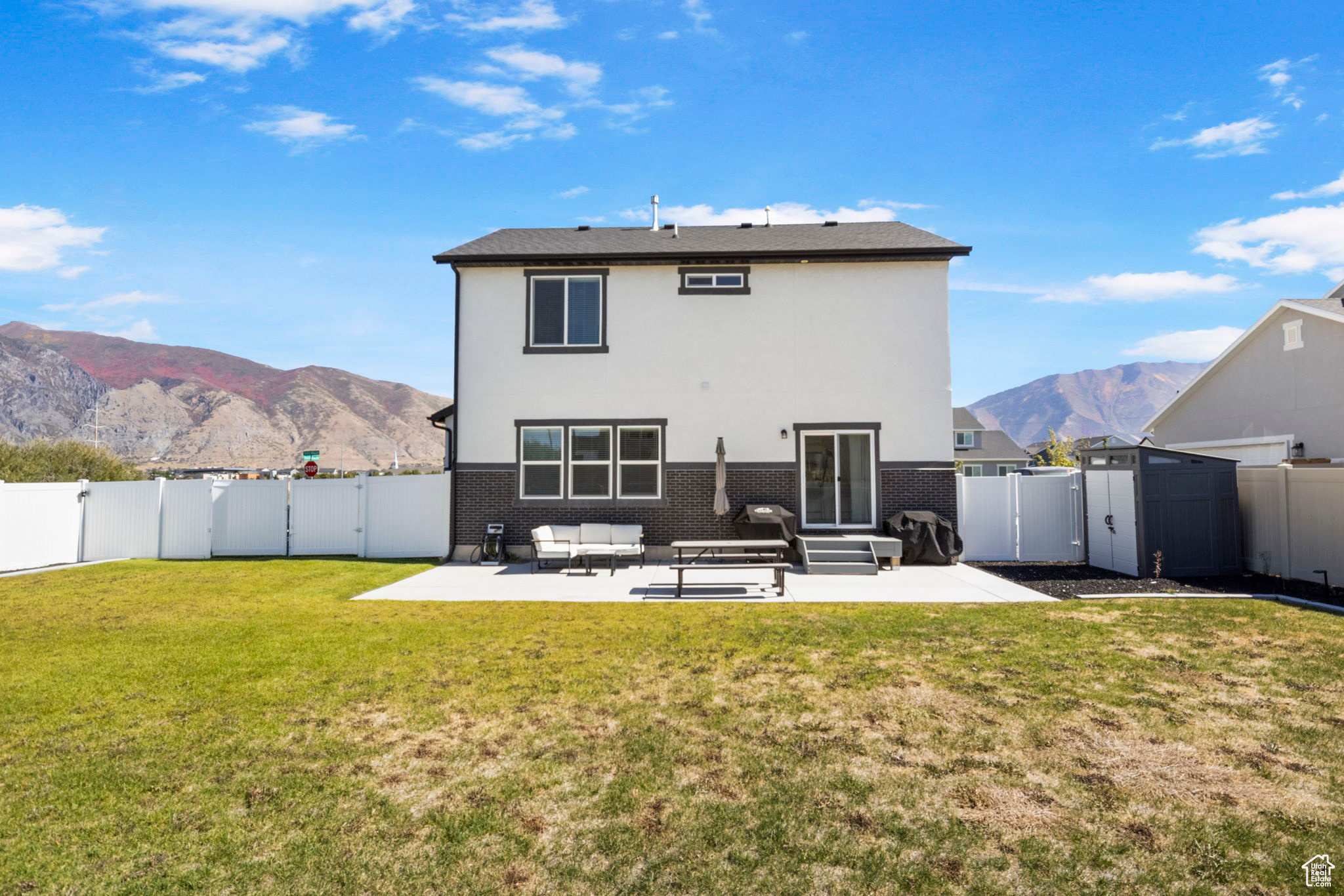 Rear view of house featuring a mountain view, a yard, and a patio