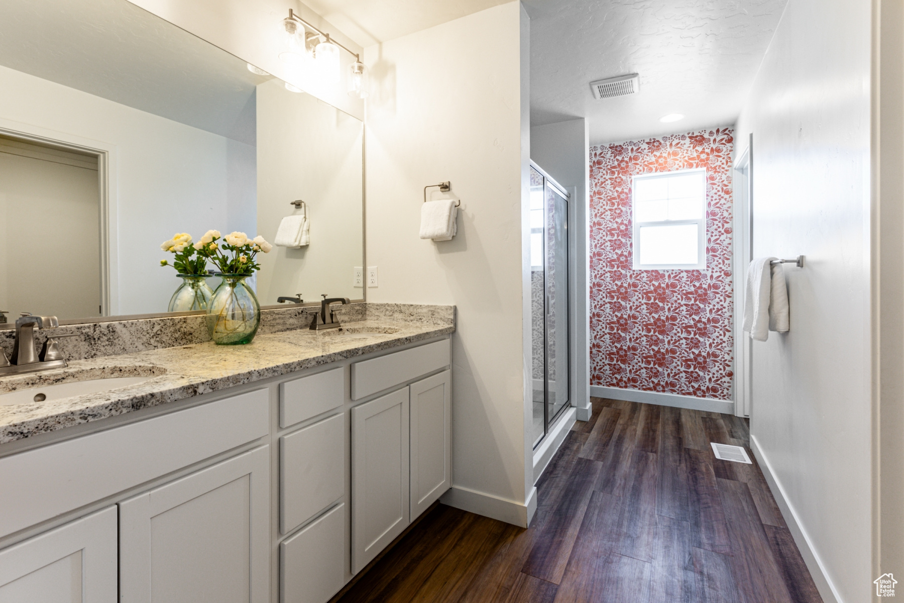 Primary bathroom featuring hardwood / wood-style flooring, a shower with door, and vanity