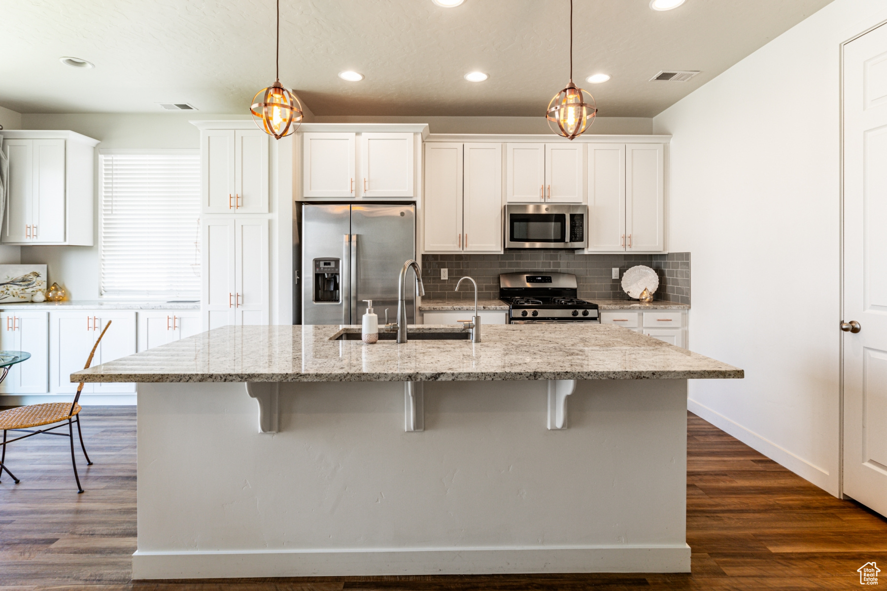 Kitchen featuring hanging light fixtures, light stone countertops, and stainless steel appliances