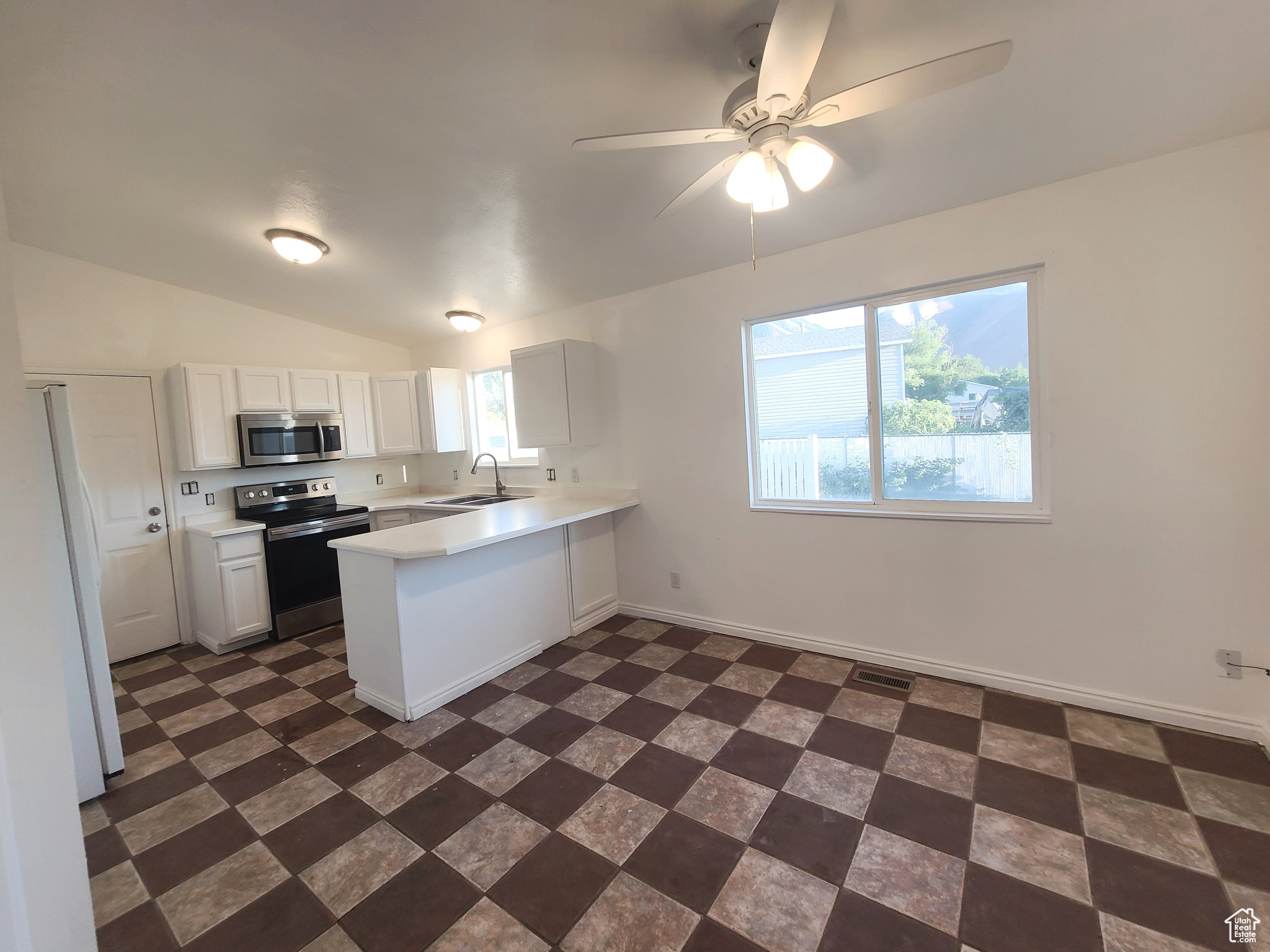 Open concept kitchen and breakfast nook with ceiling fan, white cabinets, sink, peninsula, and stainless steel appliances