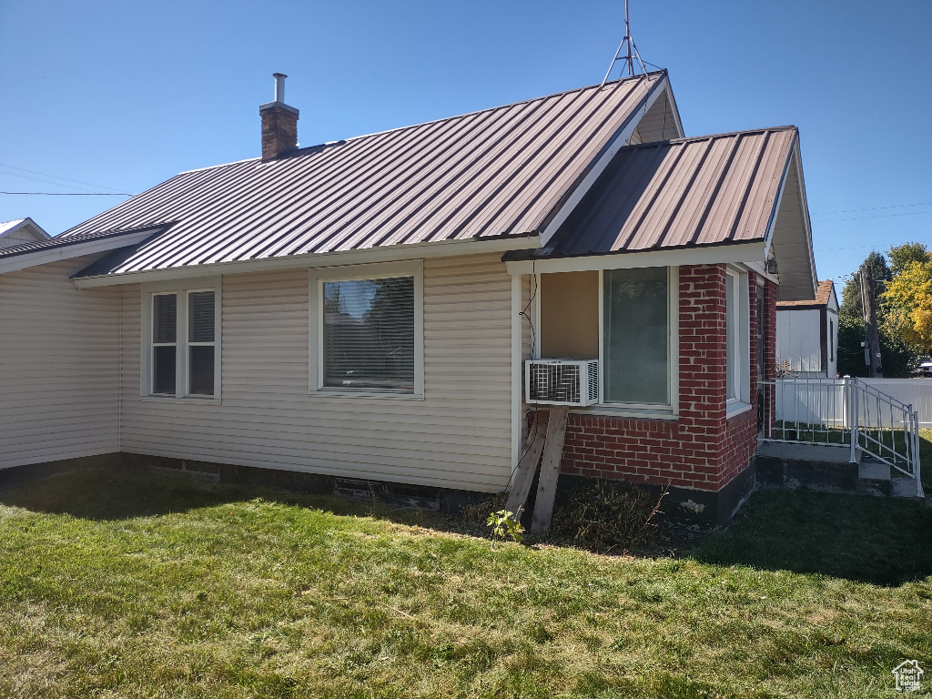 Rear view of house featuring cooling unit and a lawn