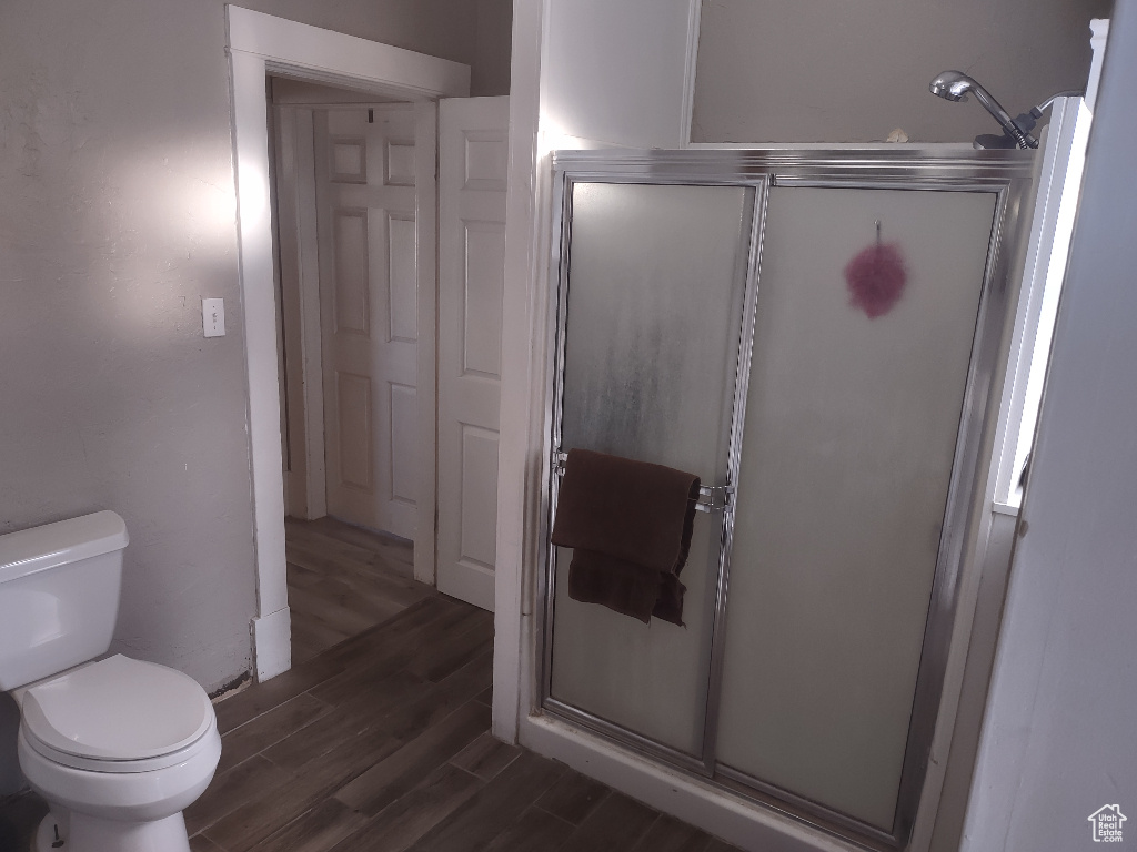 Bathroom featuring a shower with shower door, toilet, and hardwood / wood-style flooring