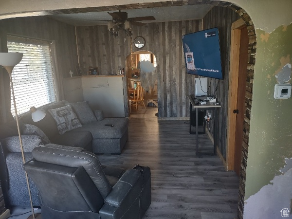 Living room with wooden walls, beam ceiling, ceiling fan, and hardwood / wood-style floors