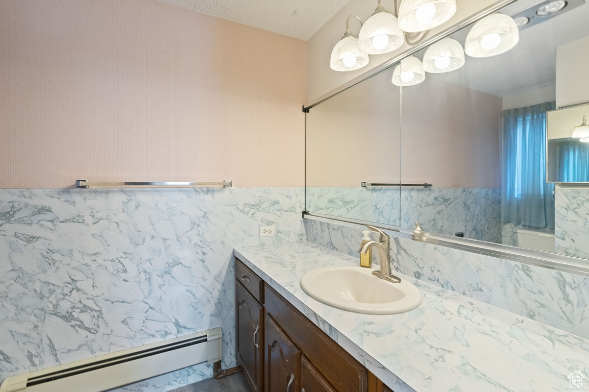 Bathroom featuring a baseboard radiator, tile walls, and vanity