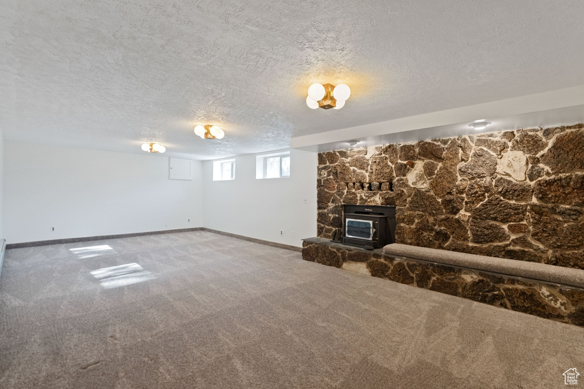 Unfurnished living room featuring carpet, a textured ceiling, and a fireplace