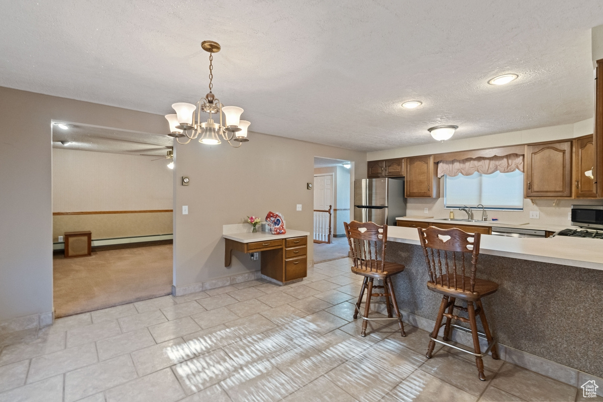 Kitchen with hanging light fixtures, sink, kitchen peninsula, stainless steel appliances, and a kitchen bar