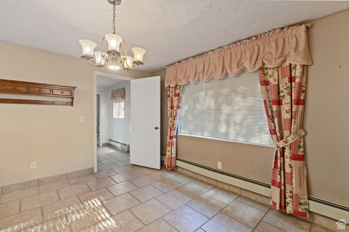 Empty room featuring an inviting chandelier and baseboard heating