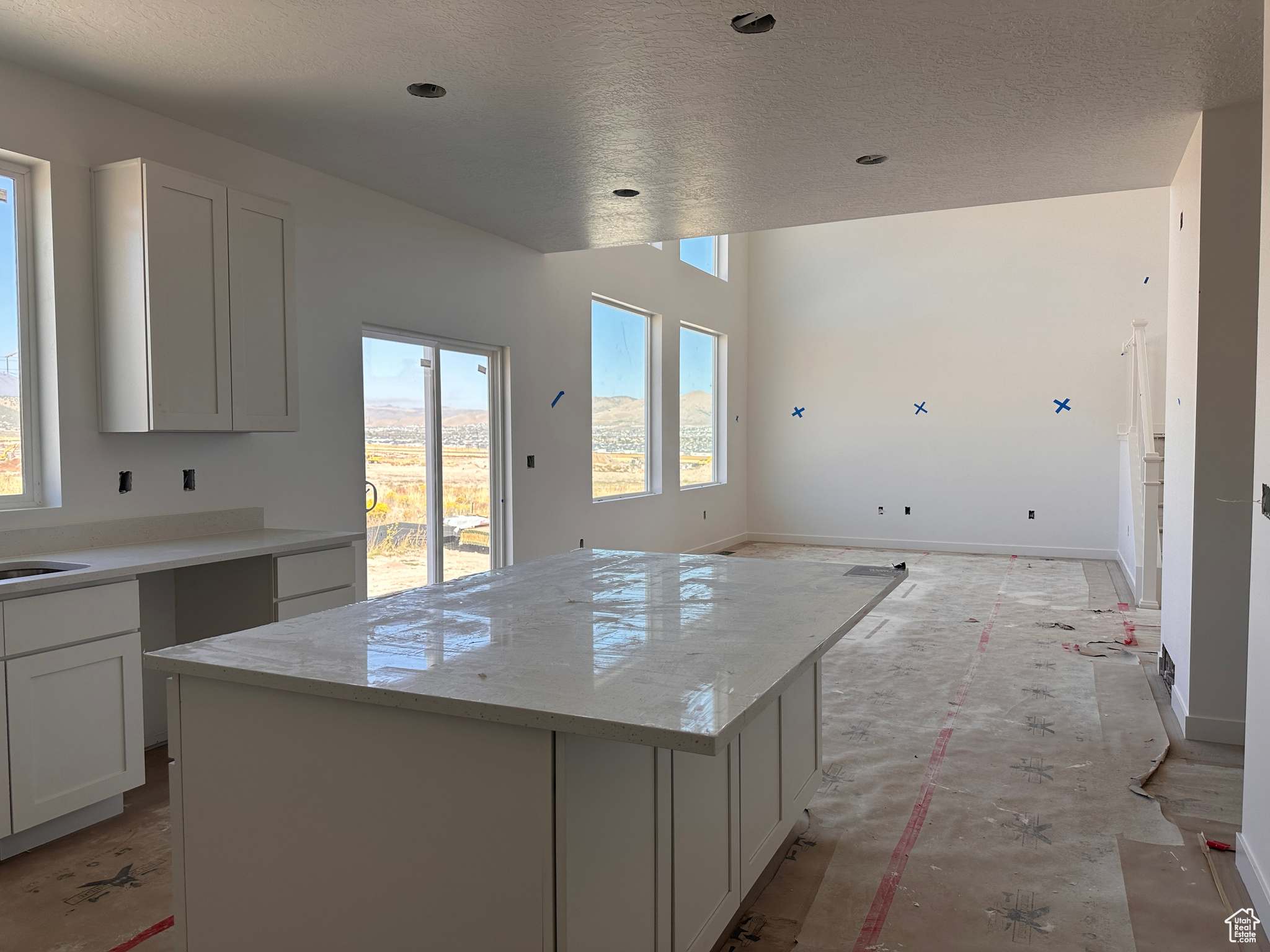 Kitchen with a textured ceiling, a center island, and white cabinets