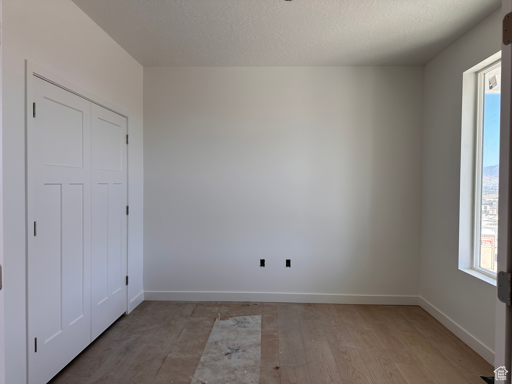 Unfurnished room featuring a textured ceiling and light hardwood / wood-style flooring