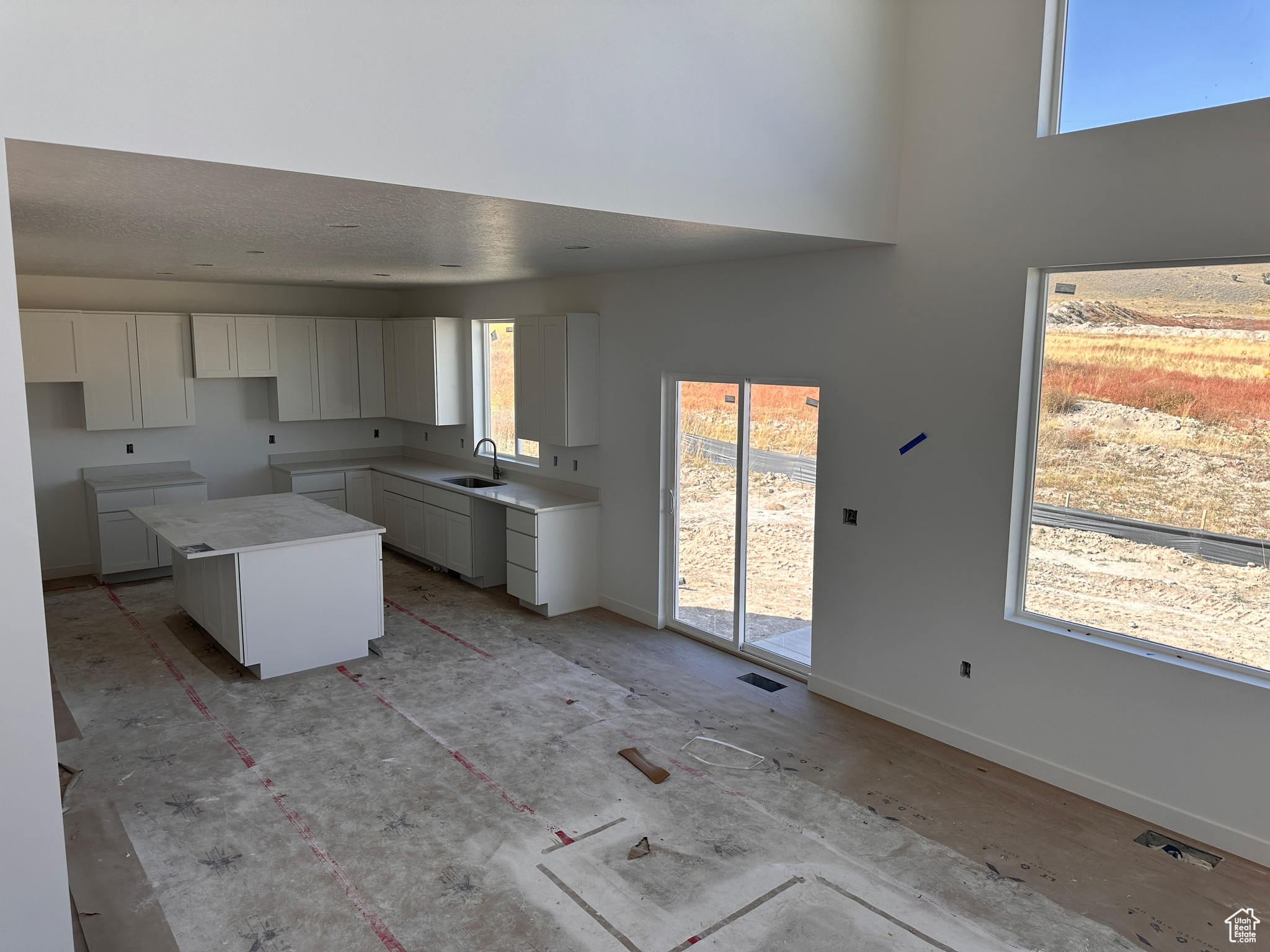 Kitchen featuring white cabinets, a textured ceiling, sink, and a center island