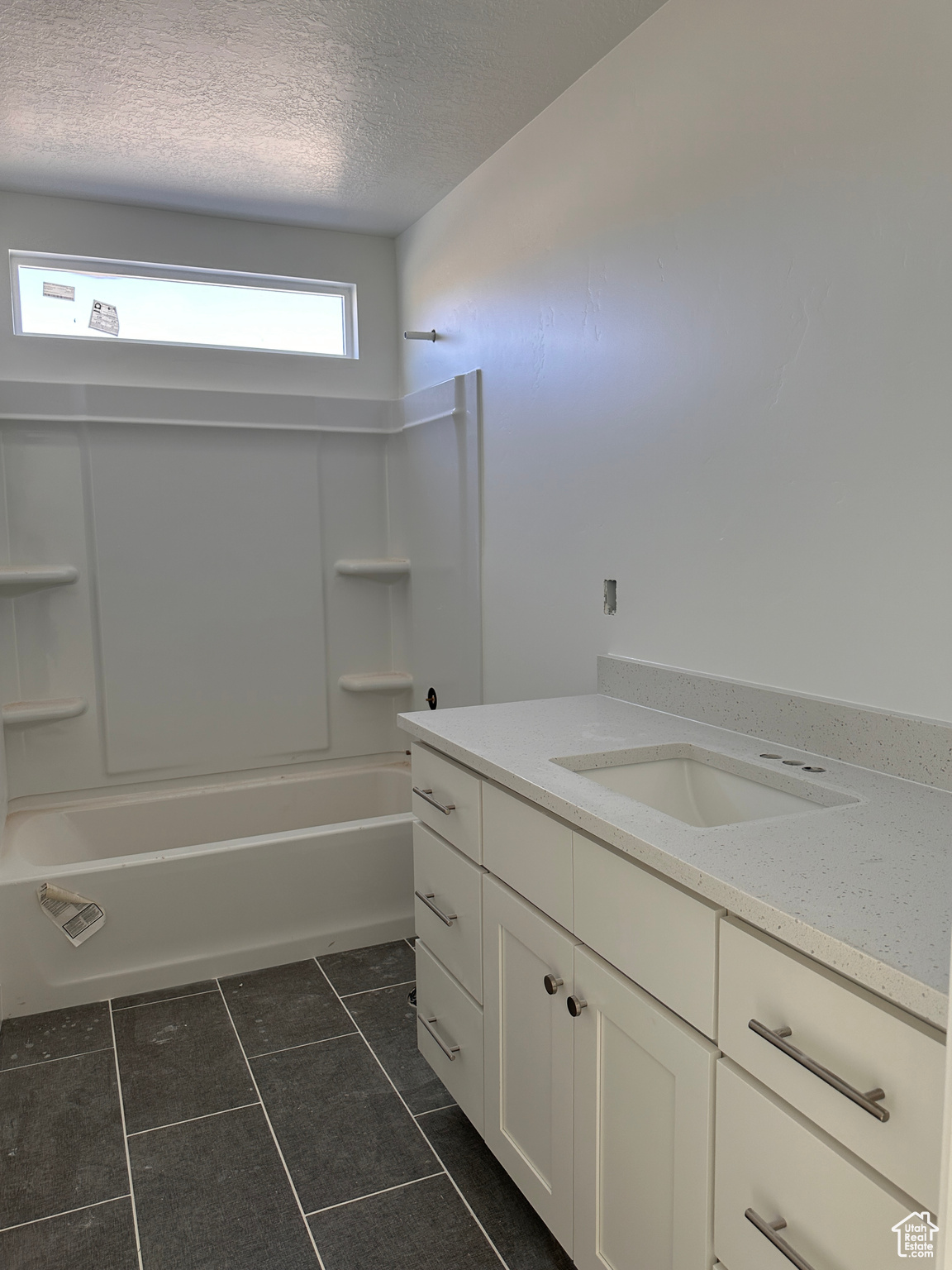 Bathroom with shower / tub combination, a textured ceiling, tile patterned flooring, and vanity