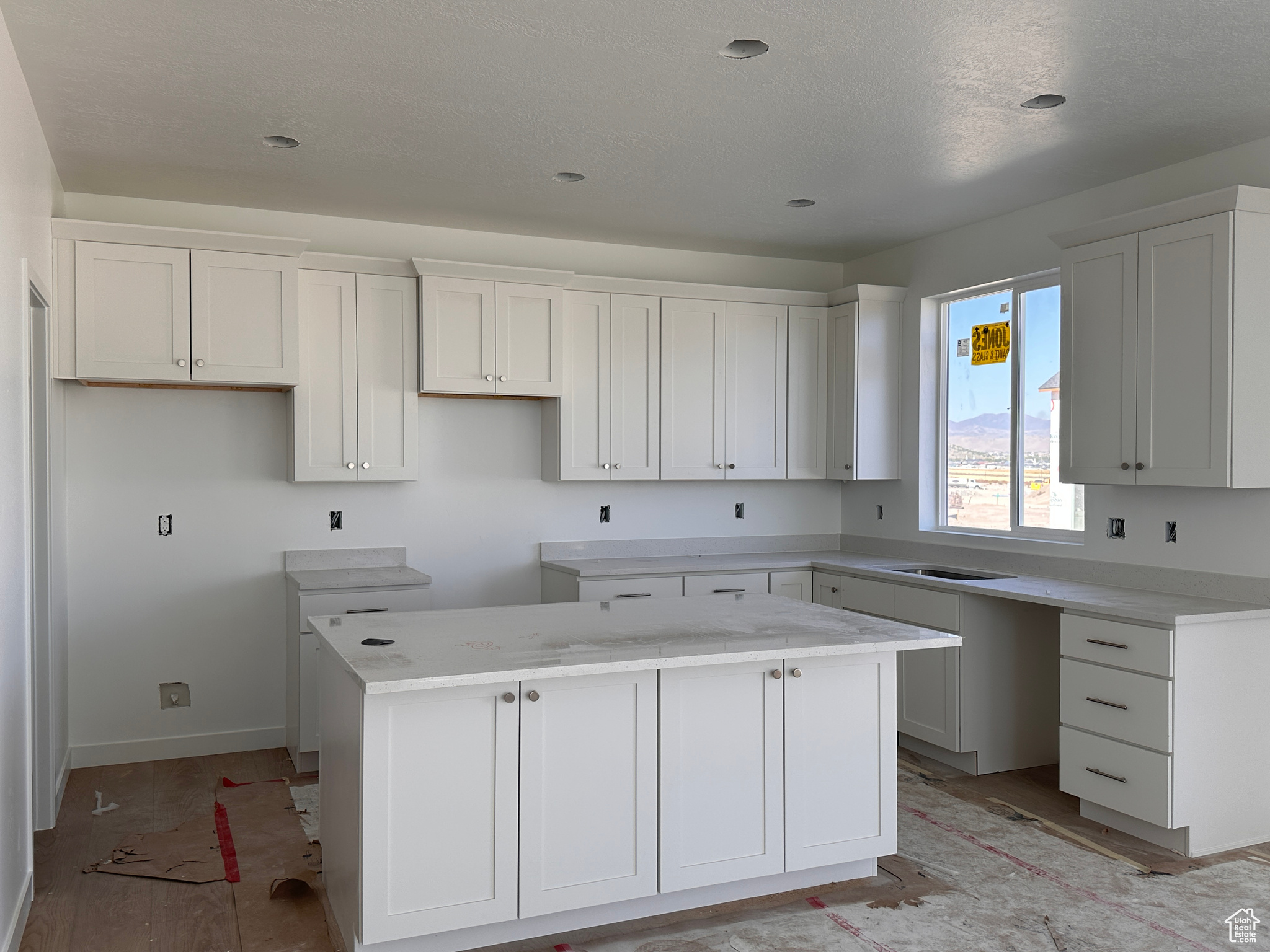 Kitchen featuring a textured ceiling, a kitchen island, light hardwood / wood-style flooring, and white cabinets