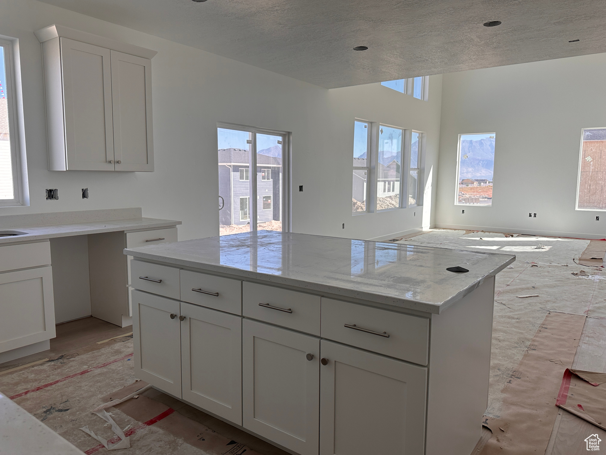 Kitchen featuring a textured ceiling, a healthy amount of sunlight, white cabinetry, and light stone counters