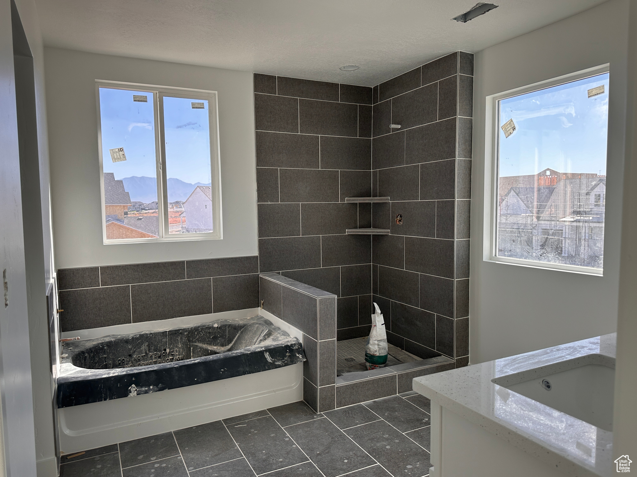 Bathroom featuring separate shower and tub, tile walls, and sink