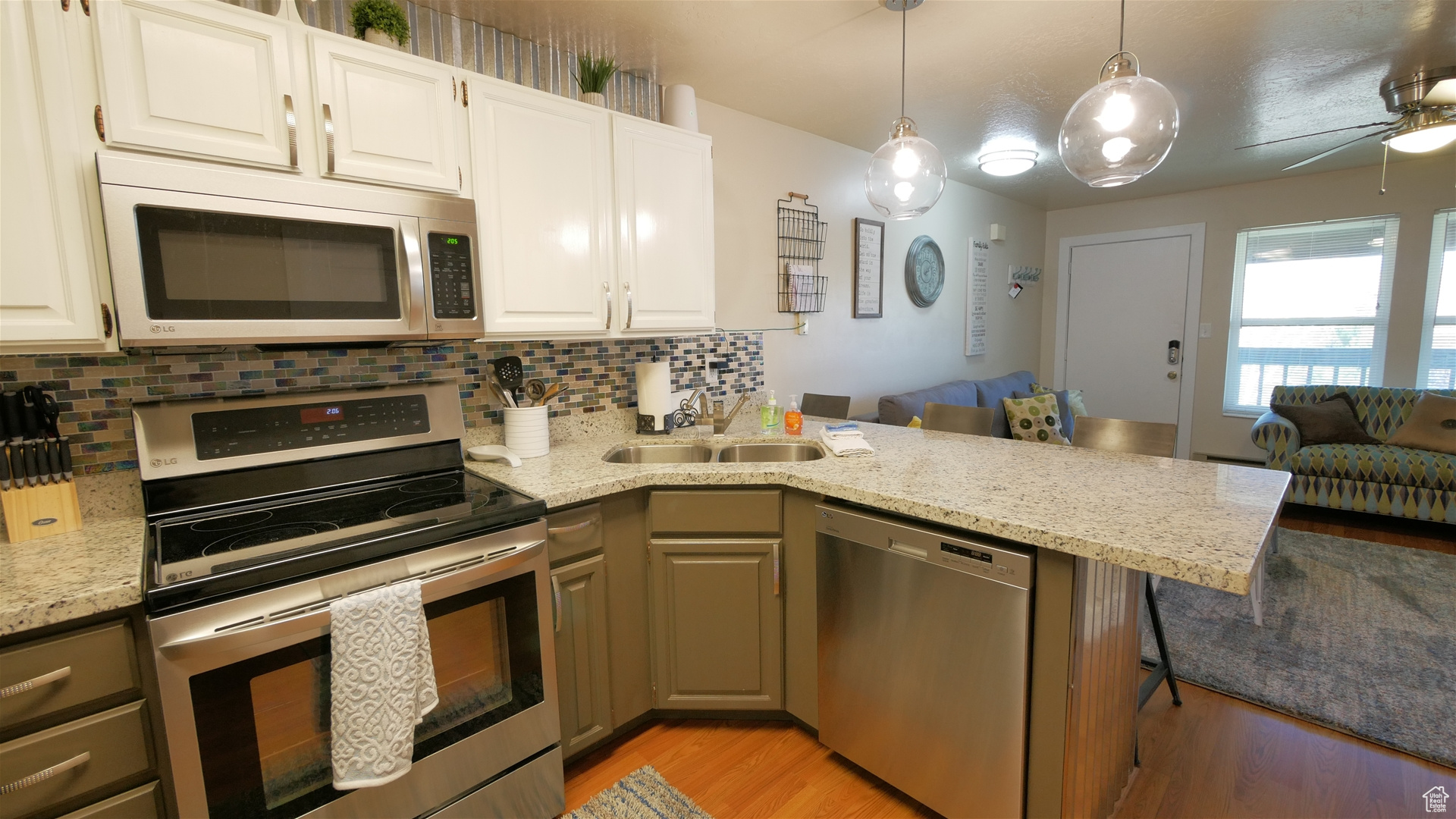 Kitchen with stainless steel appliances, white cabinets, kitchen peninsula, and ceiling fan