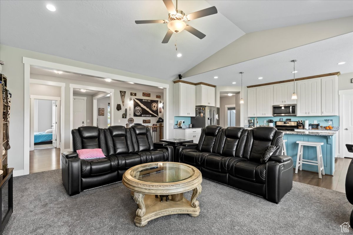 Living room featuring wood-type flooring, vaulted ceiling, and ceiling fan