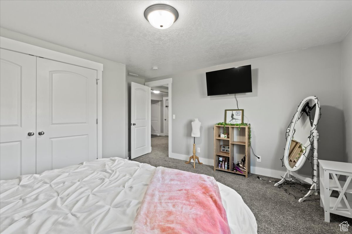 Bedroom featuring a textured ceiling, a closet, and dark colored carpet