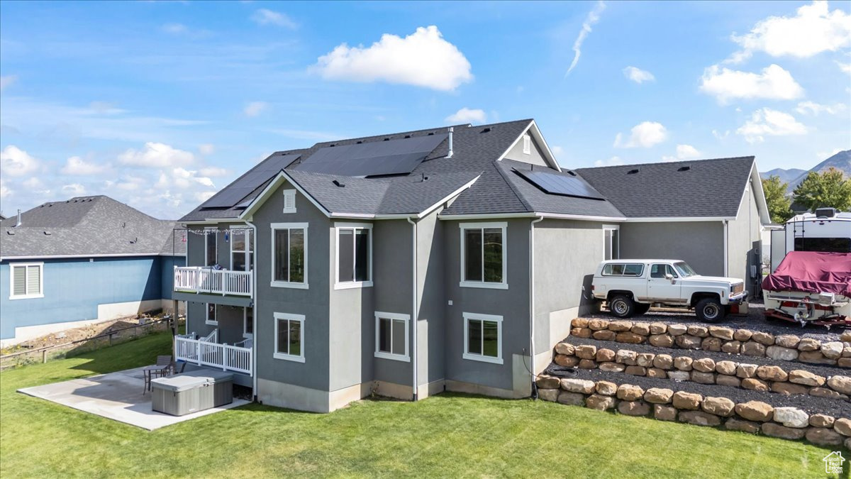 Rear view of property with a balcony, a yard, and a patio area