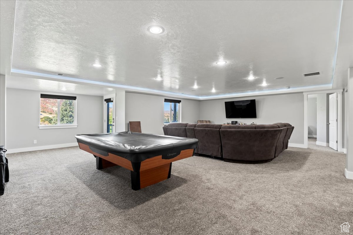 Playroom with a textured ceiling, light colored carpet, and billiards