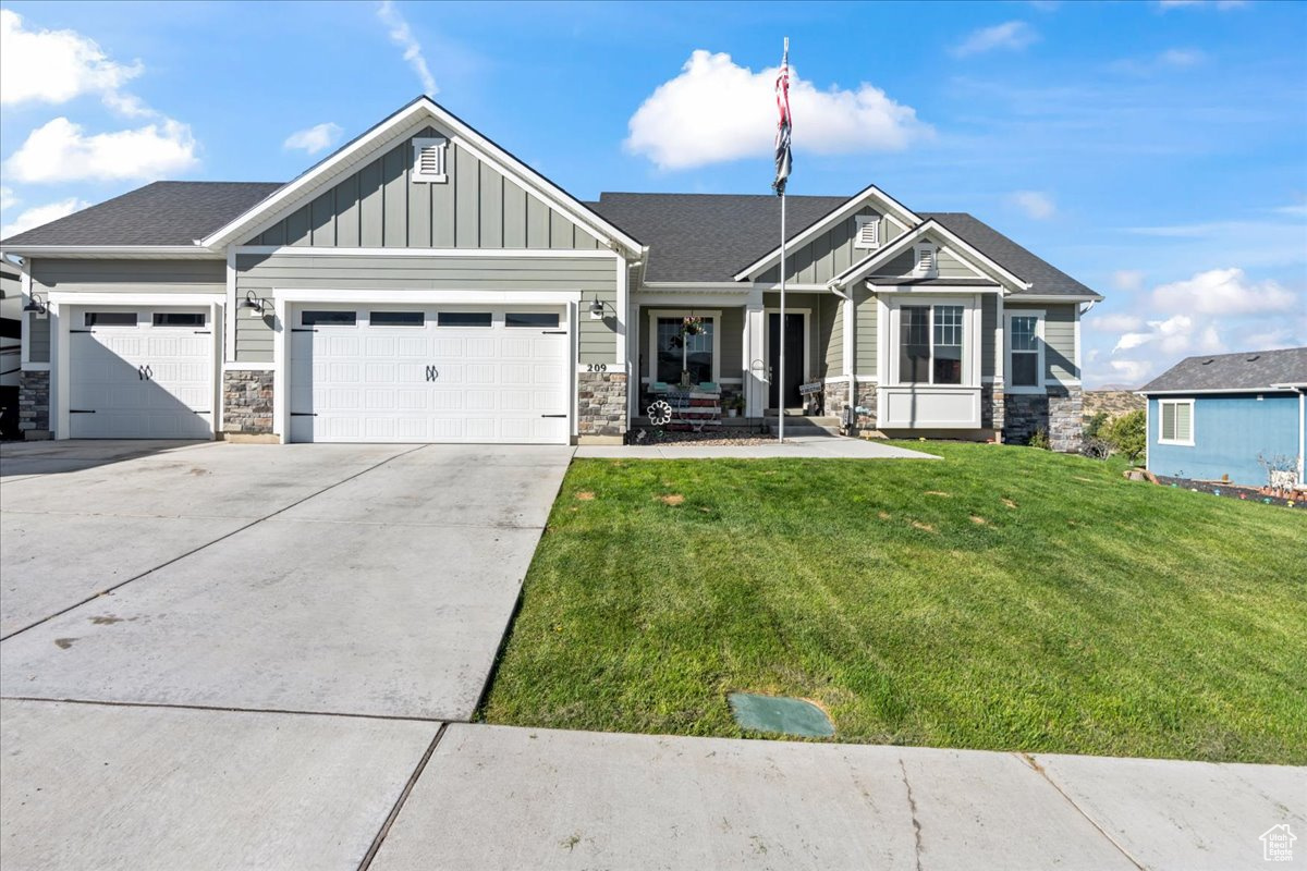 Craftsman inspired home featuring a garage and a front lawn