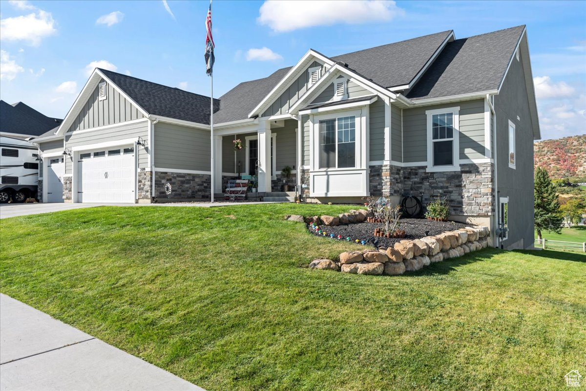 Craftsman house featuring a garage and a front lawn